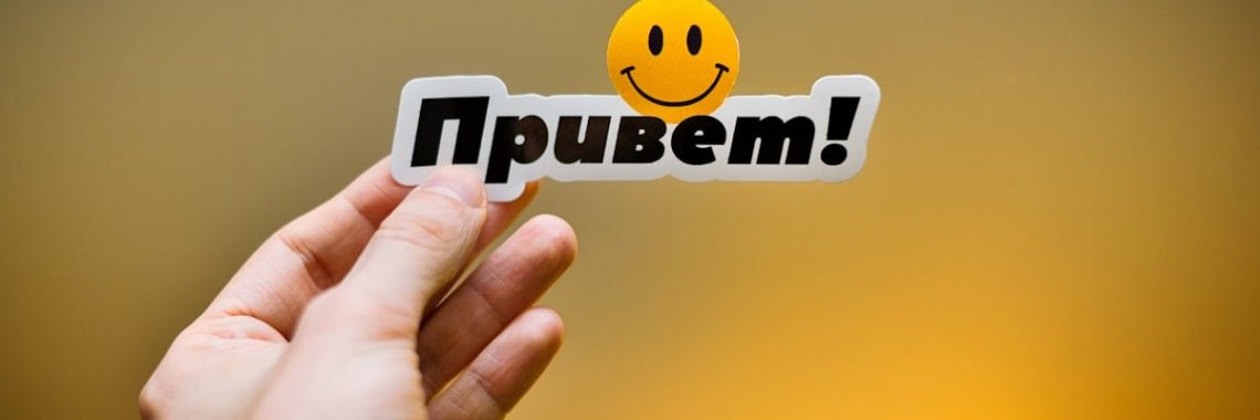 Hand holding a sticker with "привет!" and a smiley face.